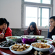 Zhao Yuqing (C) checks her mobile phone during a meal with Wang’s family.